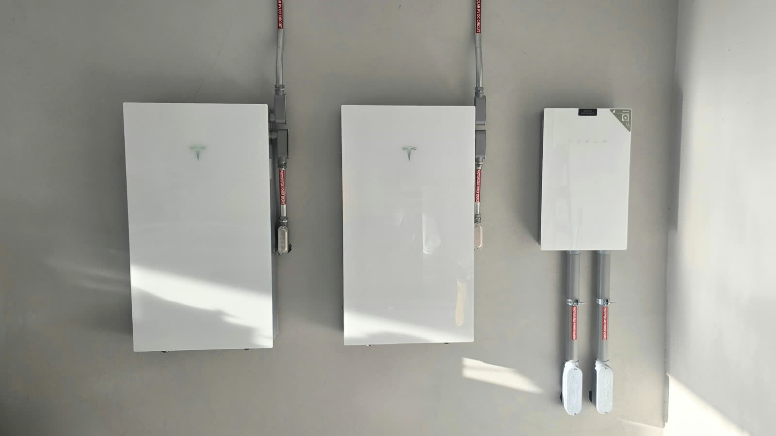 Home battery storage unit mounted on a garage wall next to a solar inverter